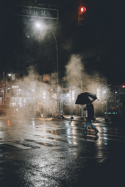 人黑夹克拿着伞在雨天走在大街上
